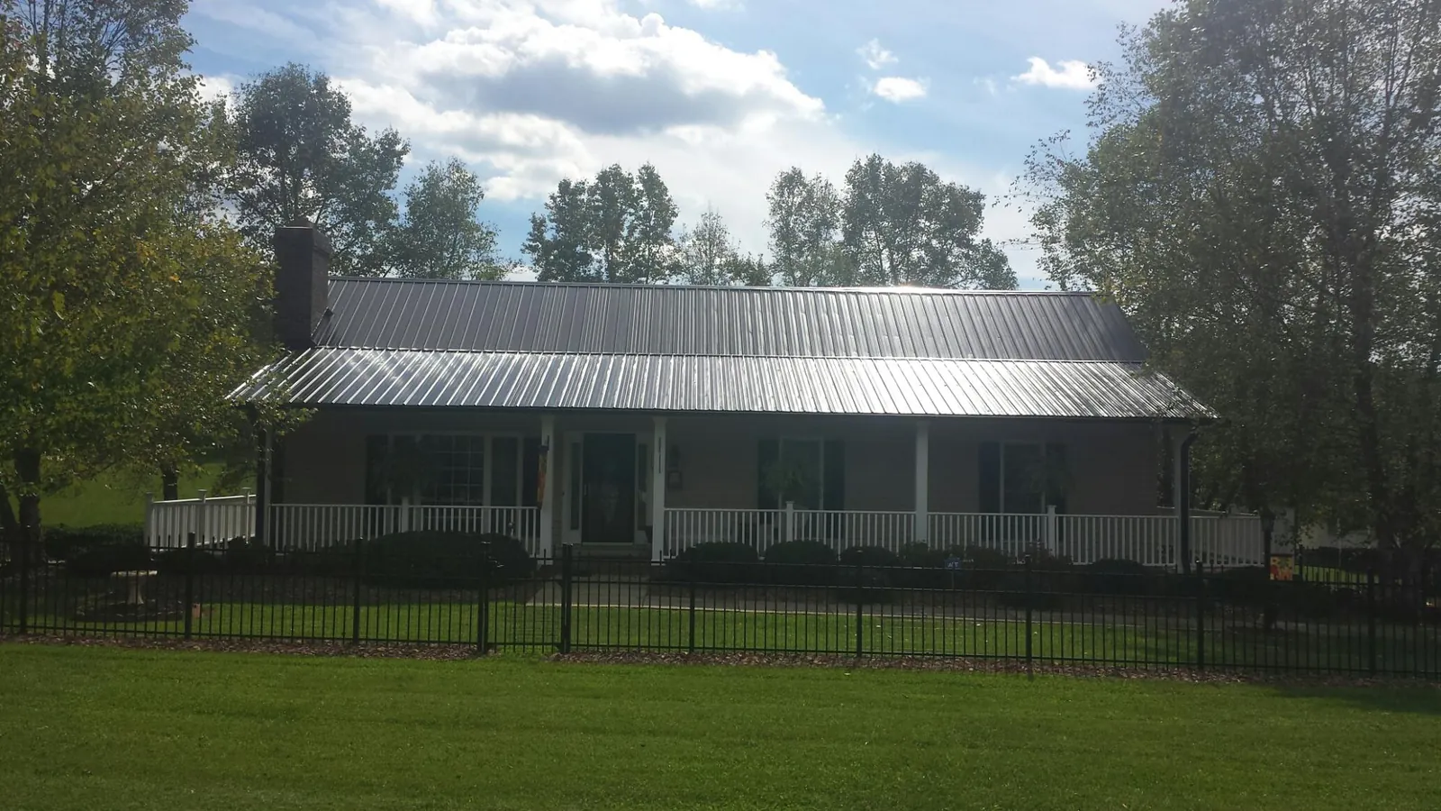 Gray metal roof on a brick ranch with a full width front porch — Gutter Guard Installation work by our crew in Sharon